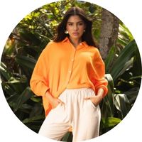 Women's oversized orange muslin blouse with a shirt collar and long sleeves, styled with beige pants – orange muslin blouse by SASSYCLASSY